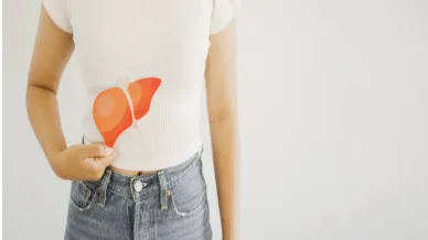 Person in a white shirt and jeans points to an orange liver illustration on their abdomen, showing liver location in the body.